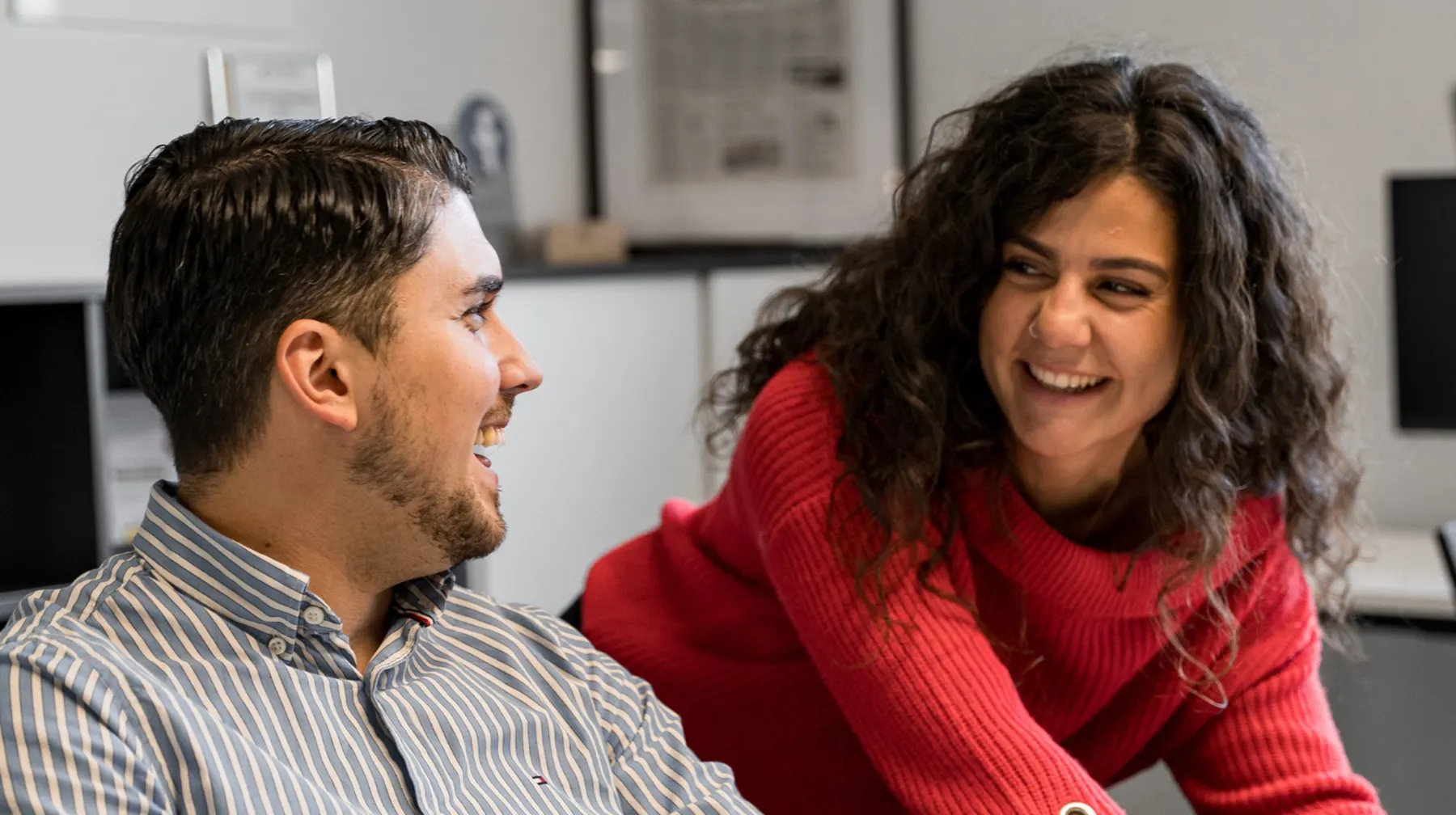Zwei Teammitglieder lachen gemeinsam am Arbeitsplatz